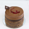 Round chocolate mousse cake topped with freeze-dried raspberry