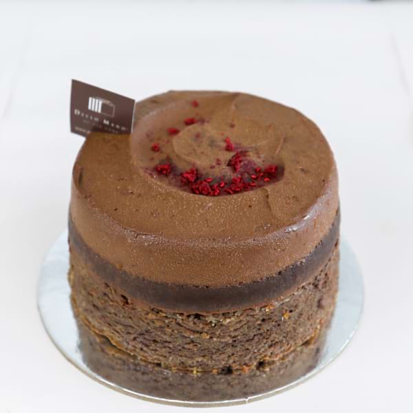 Round chocolate mousse cake topped with freeze-dried raspberry