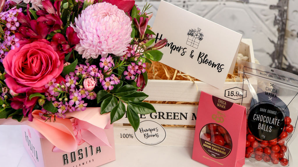 Landscape detail of pink flowers and chocolates beside a white crate and message card