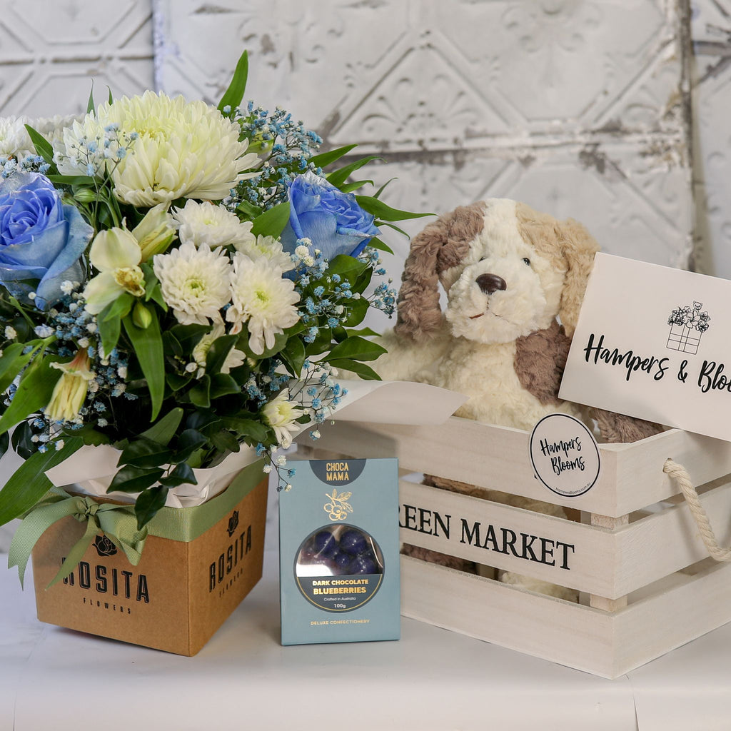 Blue and white floral pot and chocolate box displayed beside a white crate with a plush puppy and card