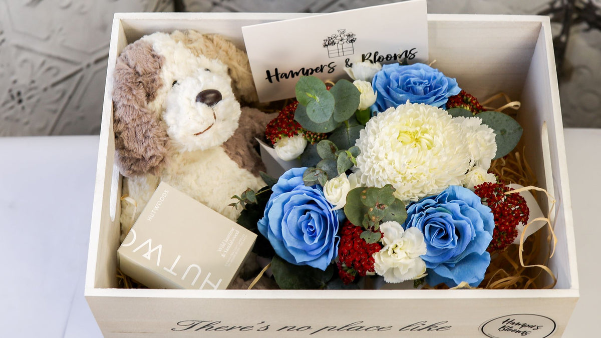 Landscape close-up of blue and white flowers, plush puppy and candle box inside a white chest