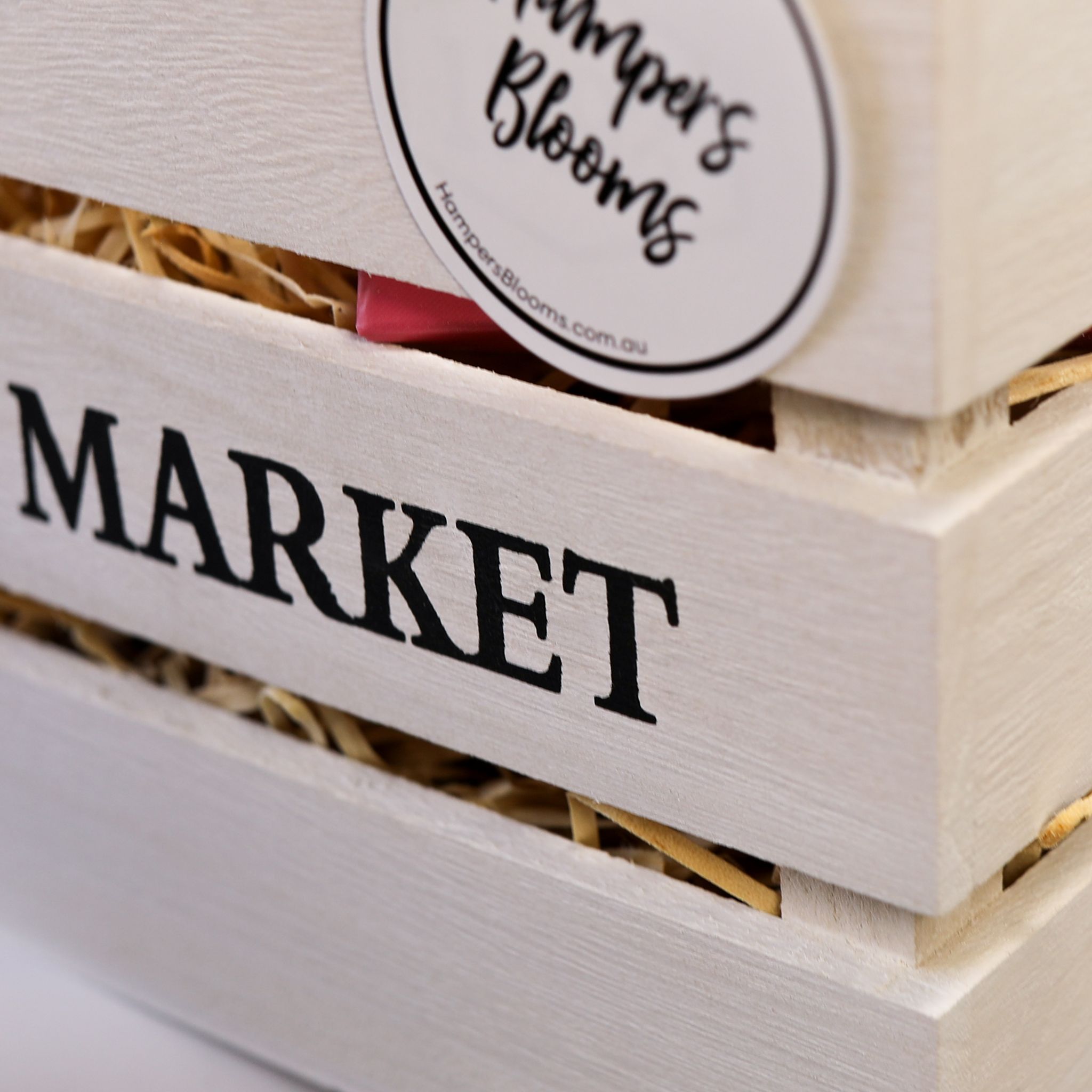 Hampers & Blooms sticker on a timber crate with straw fill
