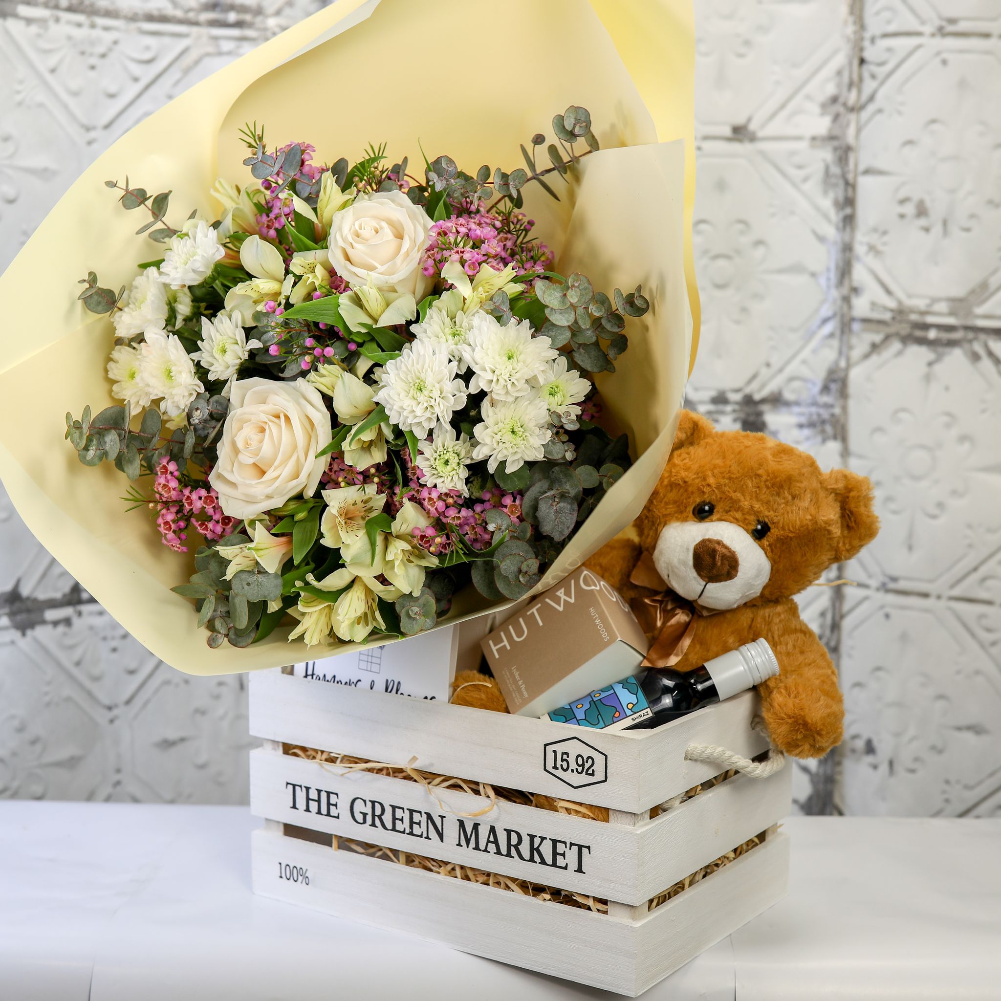 Cream and white flowers, teddy bear and gifts in a natural wooden crate
